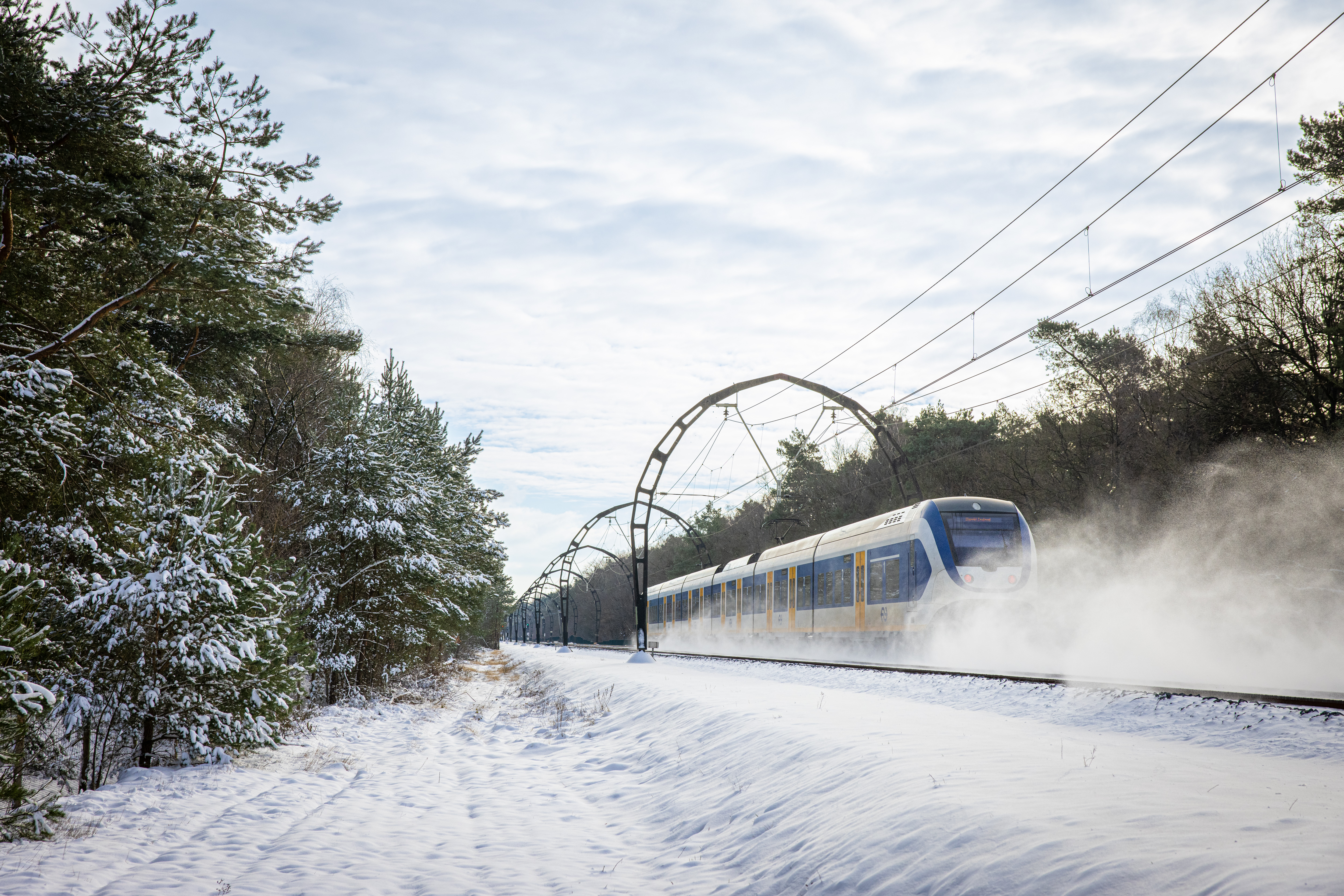 Afbeelding van een rijdende trein door de sneeuw.