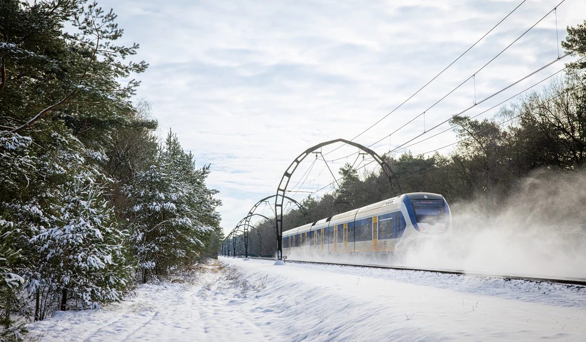Afbeelding van een rijdende trein door de sneeuw.